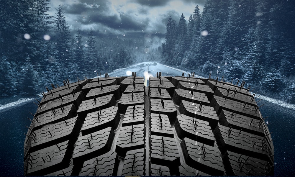 A winter tire on a snow covered road during a winter storm